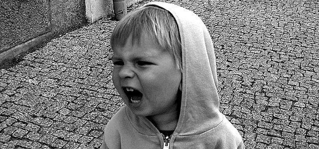 Photo of a little boy in a hooded top shouting angrily