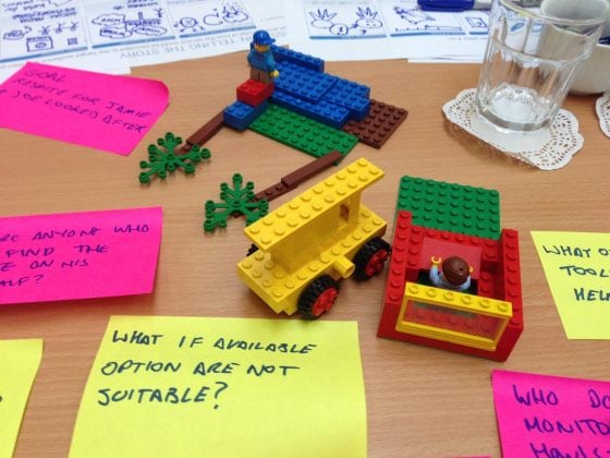 Post-it notes with questions written on them, and lego on a table