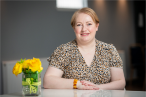 Woman sat at table with yellow flowers. 