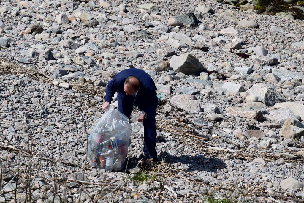 Colleague picking up litter on beach