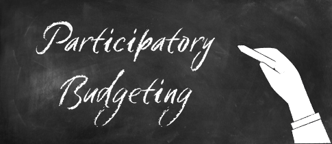 hand writing on a chalkboard, text reads "participatory budgeting"