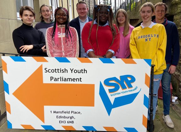 Group of MSYPs standing in from of a Scottish Youth Parliament sign