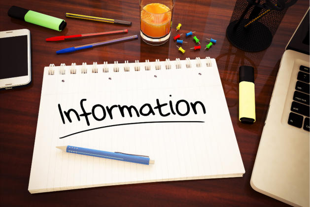 The word 'information' is written on a notepad which lies on a table top surrounded by stationery