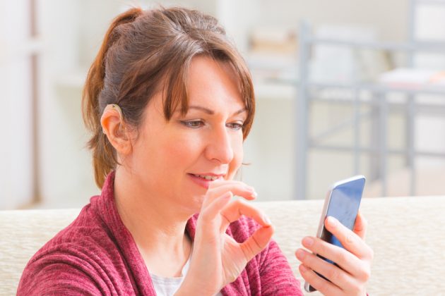 Smiling woman using sign language on her mobile phone device